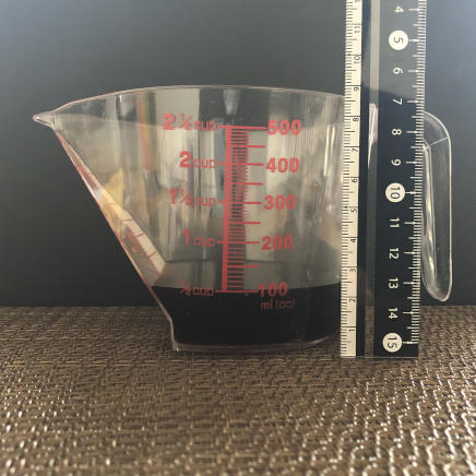 横から見た計量カップ1/2杯分のめんつゆ 107g