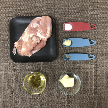 中皿1皿・1人前のチキンソテーの材料（鶏肉・塩・オリーブオイル・にんにく・バター・黒こしょう）