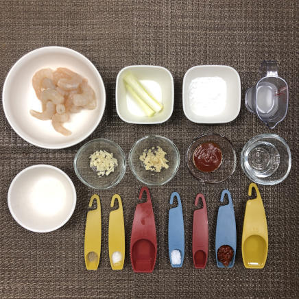 中皿1皿分・1人前のエビチリに使った材料（ムキエビ・塩・こしょう・日本酒・酢・片栗粉・卵白・サラダ油 ねぎ・しょうが・にんにく・ケチャップ・豆板醤・砂糖・水・鶏がらスープ）