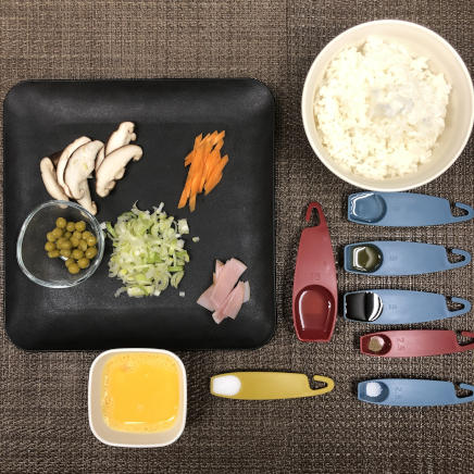 １人前の五目チャーハンに使用したご飯・ロースハム・ねぎ・人参・しいたけ・グリンピース・風味調味料・塩・こしょう・醤油・日本酒・ごま油・サラダ油・卵