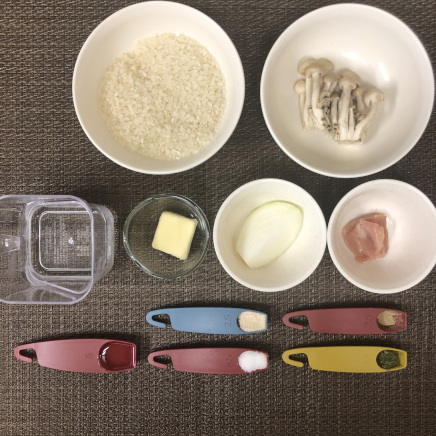1皿分のきのこピラフの材料(米・水・鶏肉・玉ねぎ・コンソメ・塩・こしょう・バター・サラダ油・パセリ・しめじ)