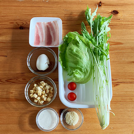 サラダボウル1杯分の水菜とベーコンのシーザーサラダに使った材料（水菜、レタス、ミニトマト、ベーコン、半熟卵、クルトン、パルメザン、シーザーサラダドレッシング）