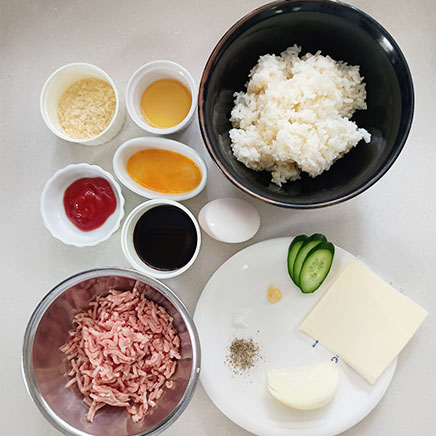 丼1杯分のチーズロコモコ丼に使用した材料（合い挽き肉、卵、玉ねぎ、おろしにんにく、塩、黒こしょう、パン粉、サラダ油、ご飯、卵（溶き卵を含む）、プロセスチーズ、ウスターソース、ケチャップ、きゅうり）