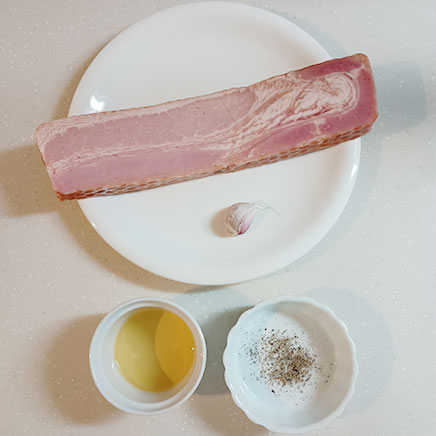 1枚分のベーコンステーキに使用した材料（ベーコン、サラダ油、にんにく、黒こしょう）