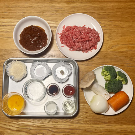 深皿(大)1皿分のシチューハンバーグに使用した材料(合い挽き肉、デミグラスソース、エリンギ、ブロッコリー、玉ねぎ、人参、パン粉、塩、こしょう、卵、水、醤油、牛乳、ケチャップ、サラダ油)