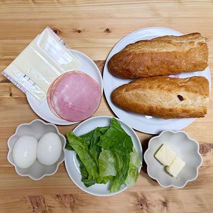 フランスパン1本分の材料（ハムとたまごとチーズのバゲットサンドに使ったフランスパン、ロースハム、ゆで卵、プロセスチーズ、レタス、バター）